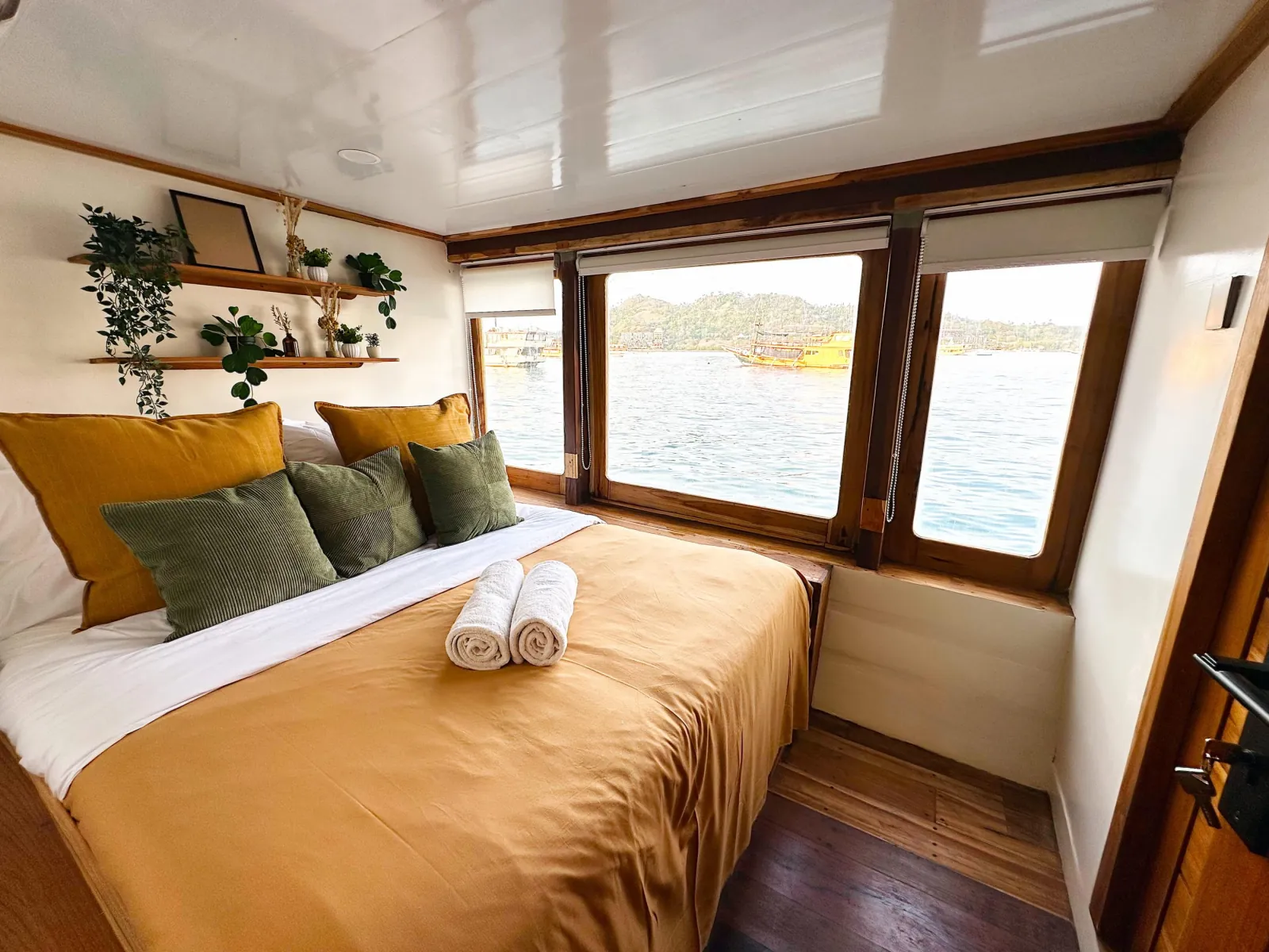Double cabin with sea-view windows and folded towels aboard the Komodo Phinisi