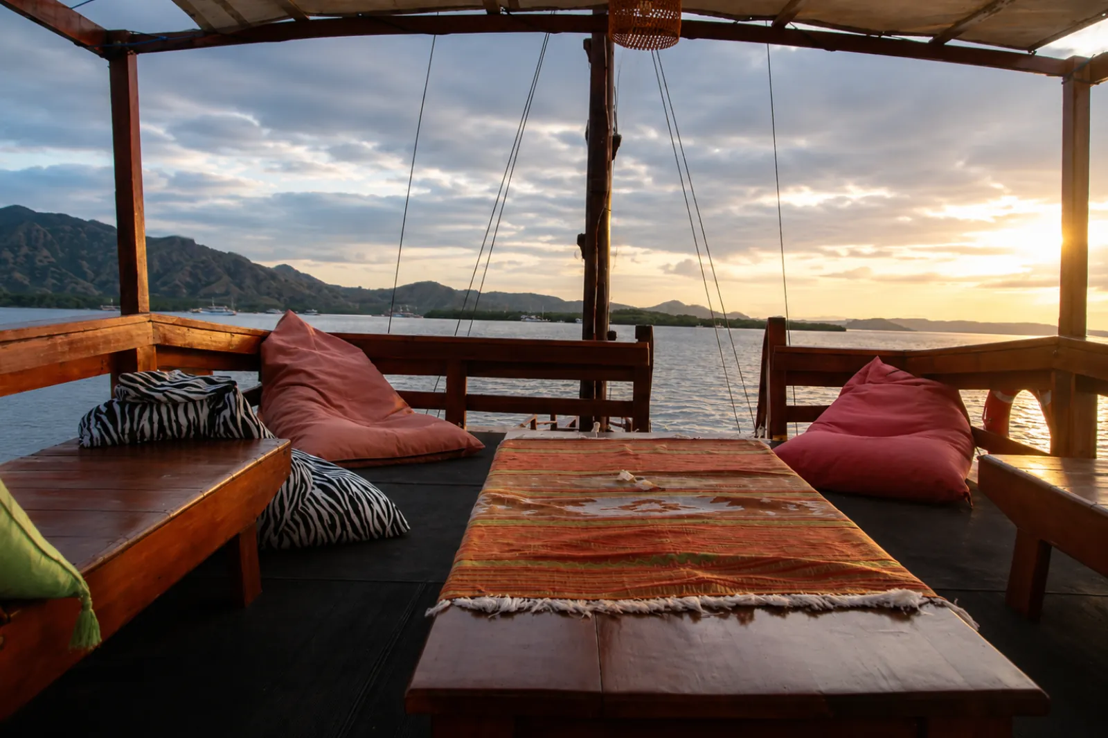 Open-air lounge deck with cushions and a low table on a Komodo liveaboard