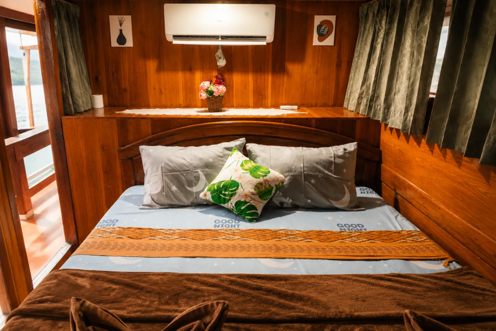 Private double cabin with timber panelling aboard a Komodo boat