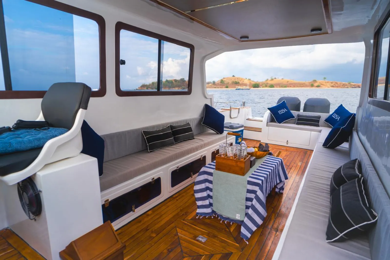 Shaded rear deck with cushioned bench seating on a Komodo day boat