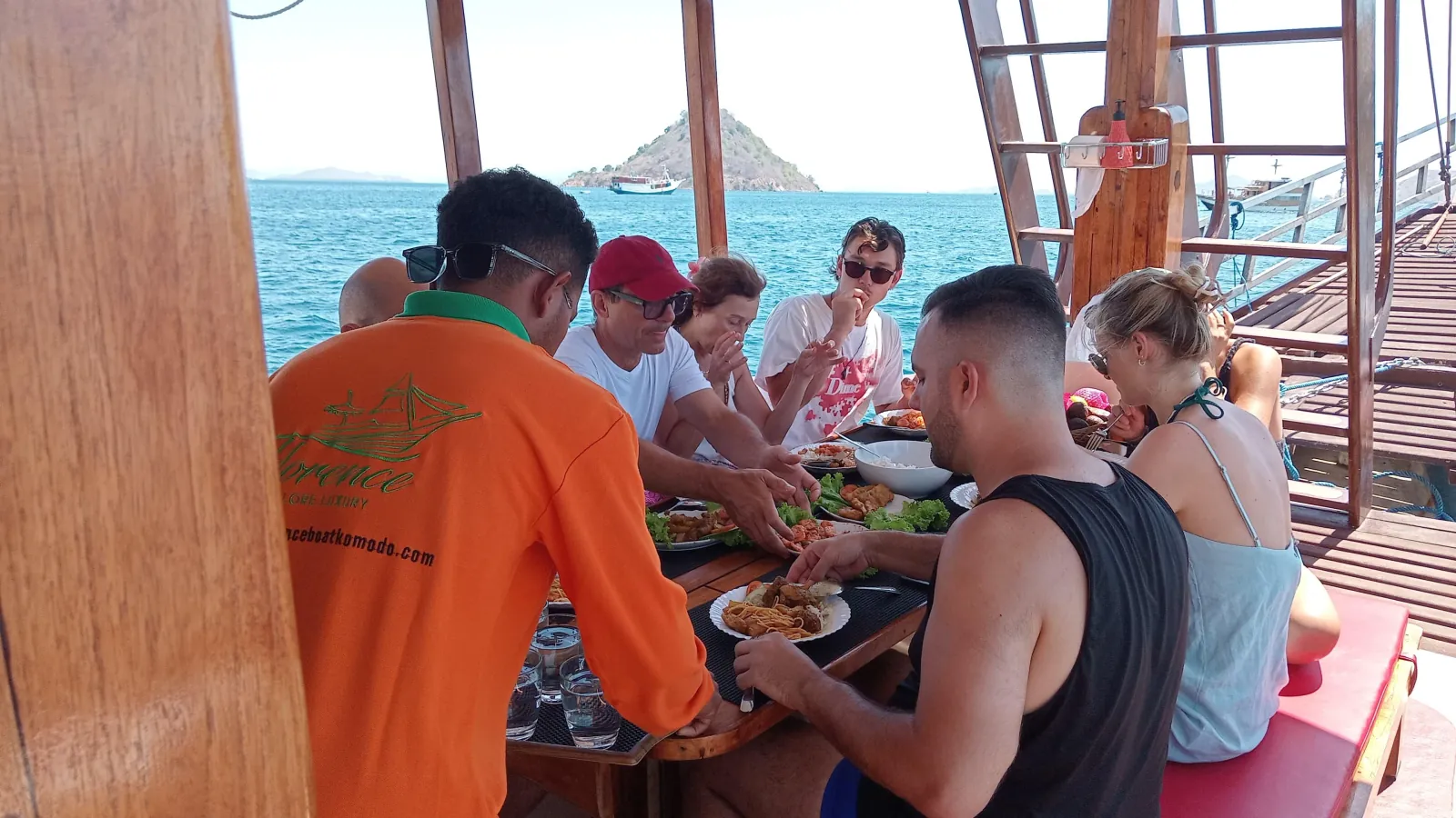 Guests sharing a meal at the table on the deck of a shared Komodo boat