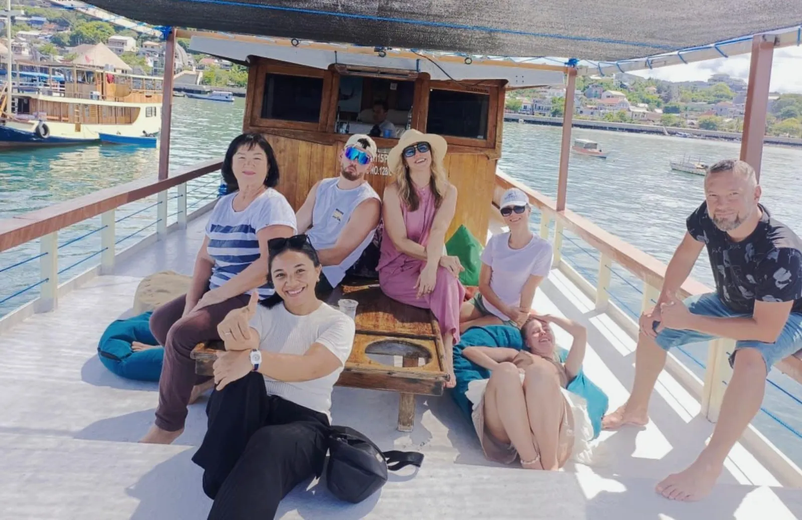 Group of travellers relaxing on bean bags on the shaded deck of a Komodo boat