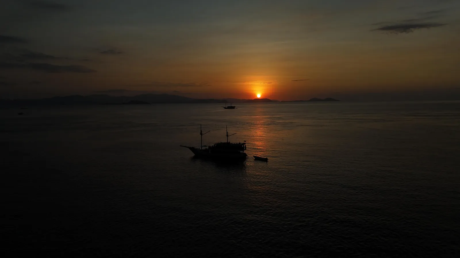 Phinisi liveaboard silhouetted against the sunset off Labuan Bajo