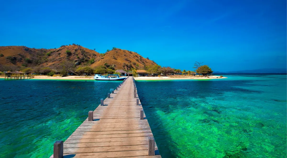 Timber jetty leading to a small island in Komodo National Park under deep blue sky